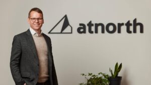 Eyjolfur stands in front of a wall with the "atnorth" logo and a small plant.