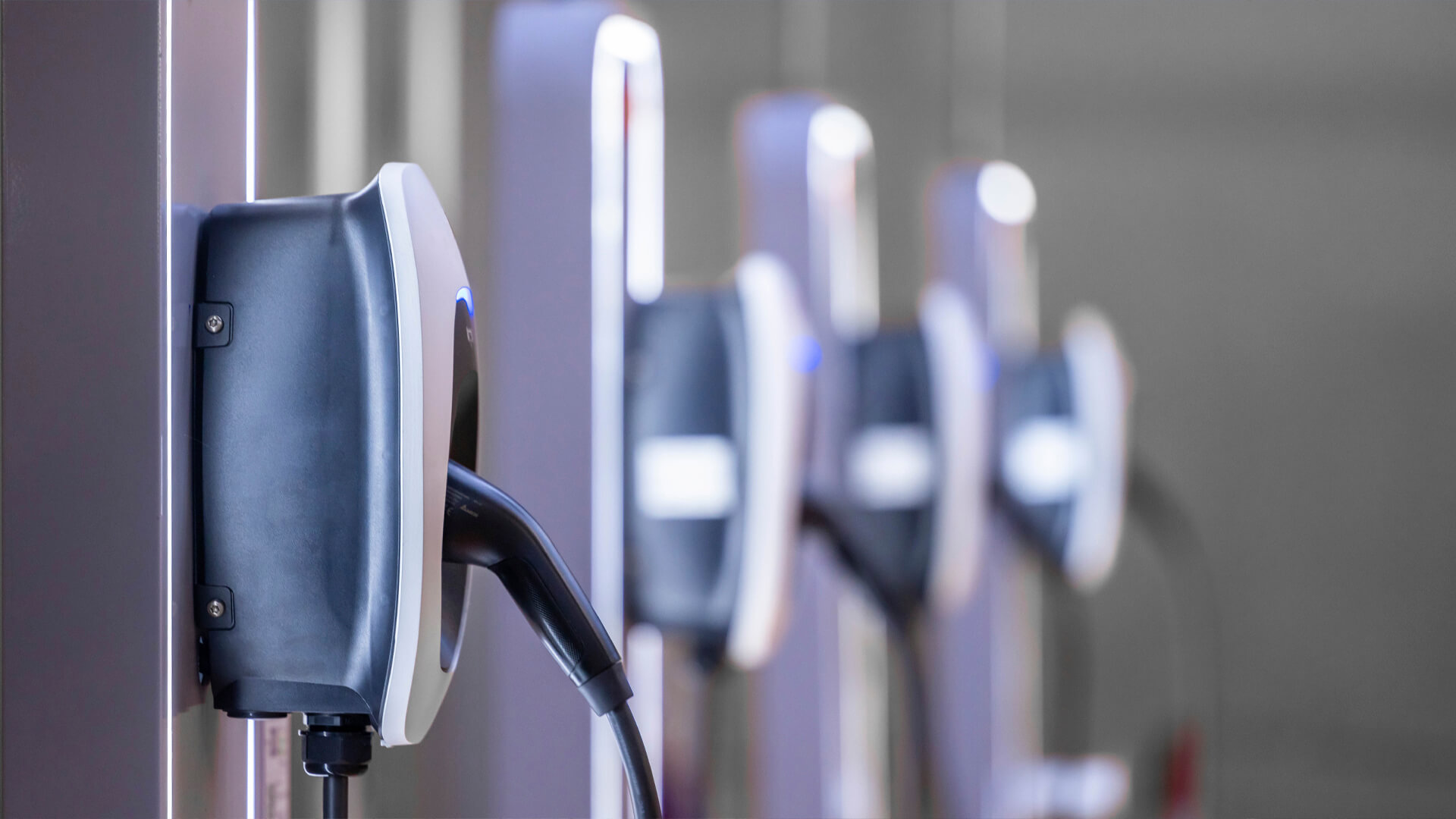 Close-up of multiple electric vehicle charging stations lined up in a row, each equipped with a charging cable, resembling the precision and organization of a data center.
