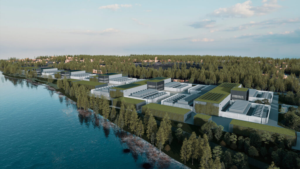 Aerial view of an industrial facility, possibly a data center, nestled among trees and located near a serene body of water, with a clear sky overhead.