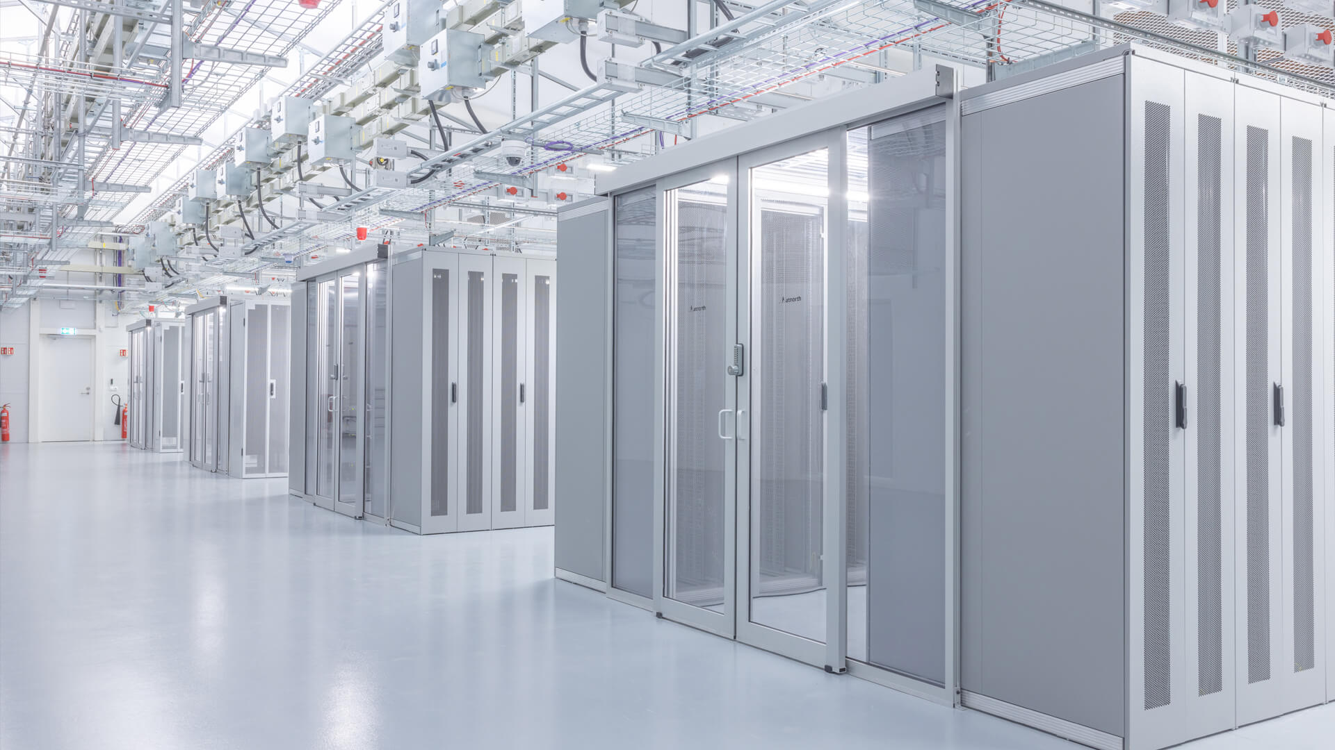 A cutting-edge data center showcasing rows of sleek grey server racks and organized cable trays adorning the ceiling, all within a well-lit, pristine environment.