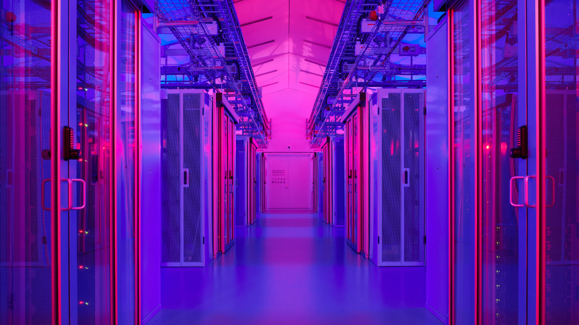 The data center's hallway, adorned with rows of server racks, is bathed in a mesmerizing blend of purple and blue lights.