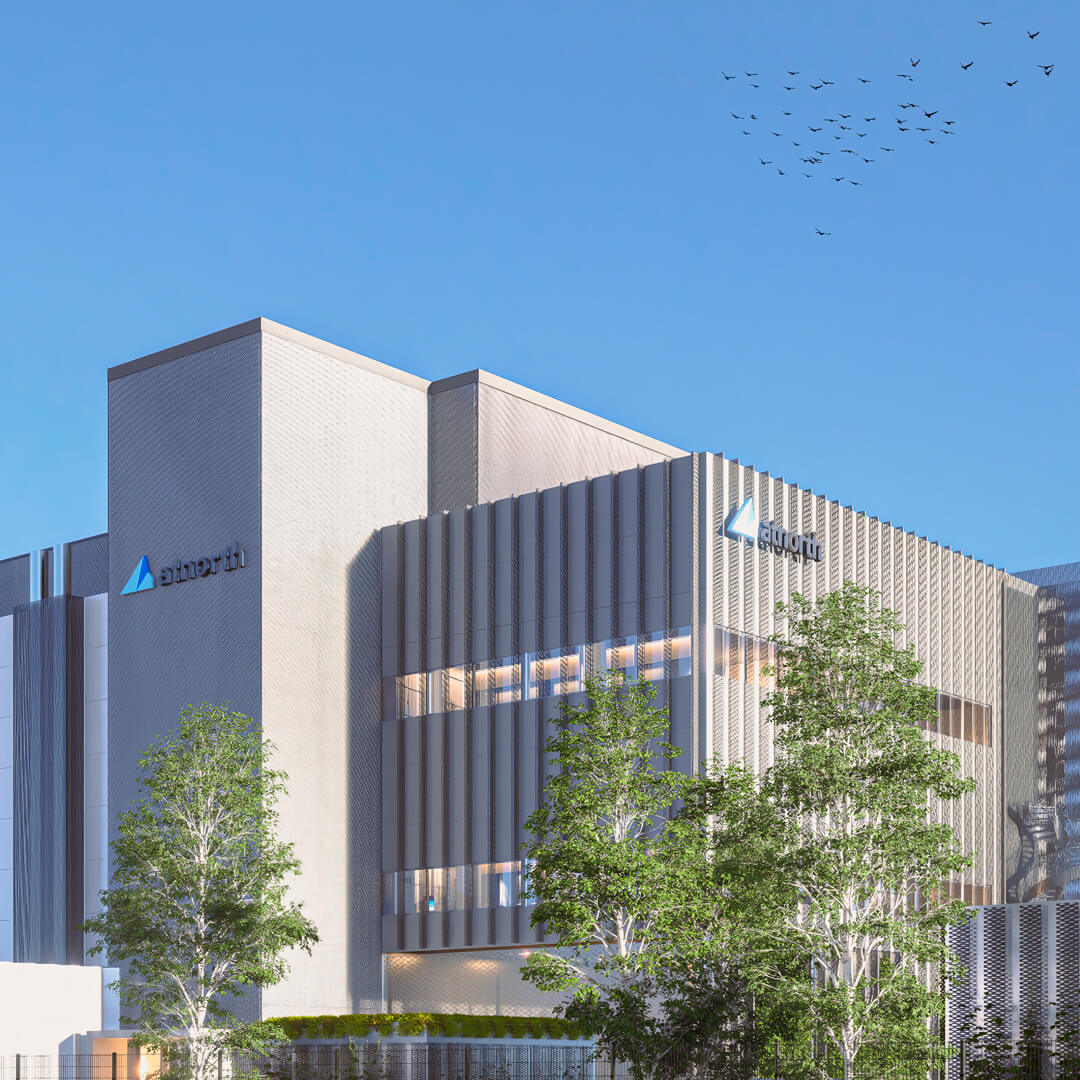 A modern data center with a gray facade and geometric design, surrounded by trees under a clear blue sky. Birds are flying in the top right corner.