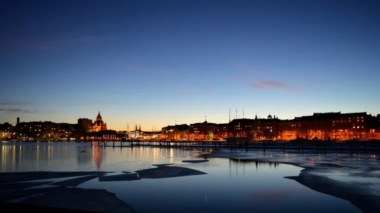 Night view of a city skyline reflecting on a calm, partially frozen body of water with clear skies, where the glowing lights resemble a bustling data center.