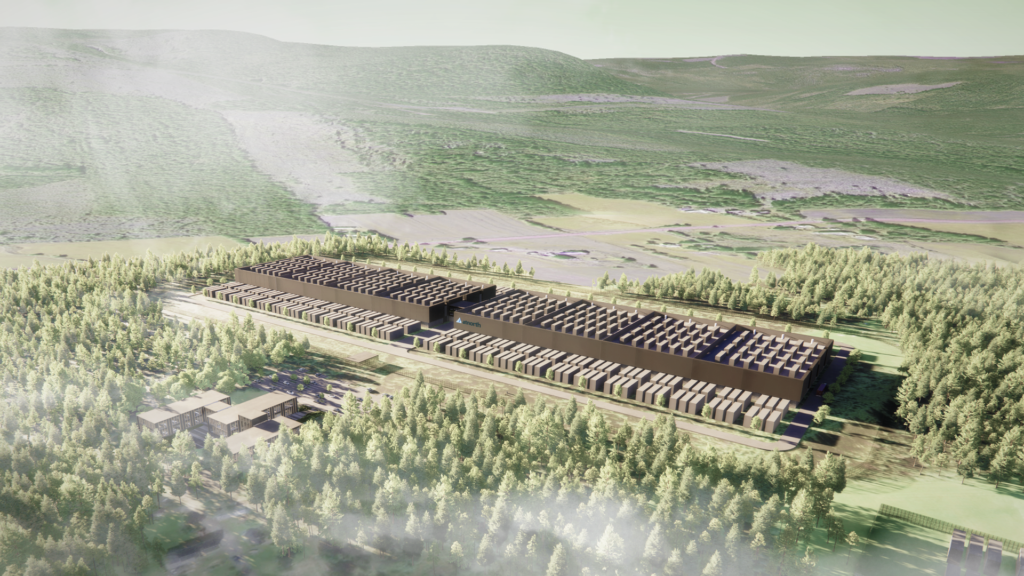 Aerial view of a large industrial facility surrounded by dense forest and hills under a misty sky.