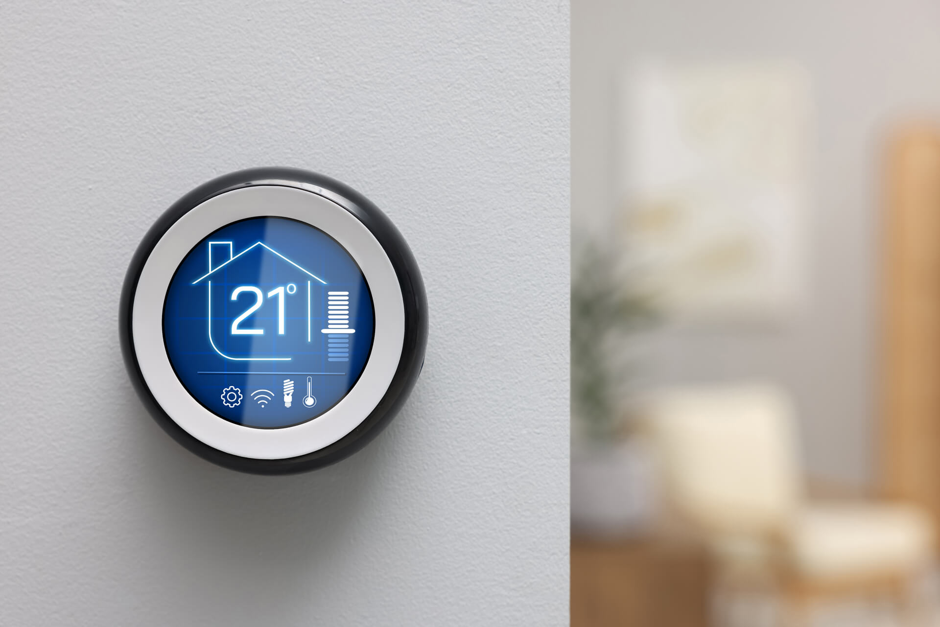 A smart thermostat on a wall displays a temperature setting of 21°C with icons for home, fan, and temperature controls.
