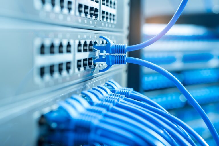 Close-up of blue network cables connected to ports on a server in a data center.