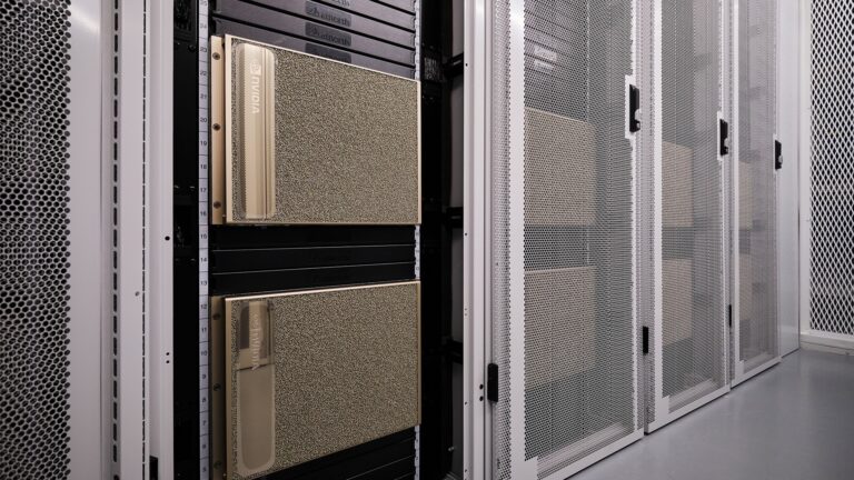 Close-up view of NVIDIA server hardware installed in a data center rack, surrounded by metal mesh cabinet doors and industrial flooring.