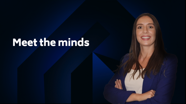 A woman in business attire stands with arms crossed and smiles next to the text "Meet the minds" on a dark blue geometric background.
