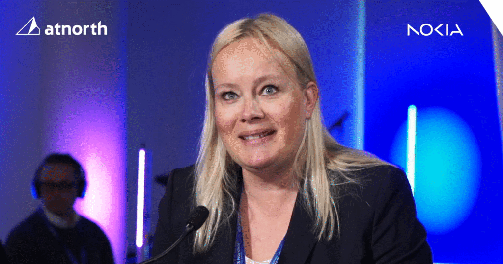 A woman with blonde hair speaks at a microphone during an event. The atnorth and Nokia logos are visible on the top corners against a blue and purple background.