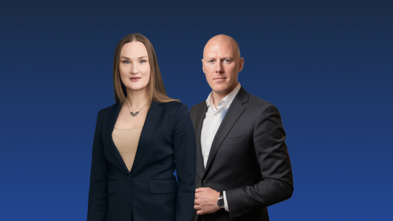 A woman and a man in business attire stand side by side against a blue gradient background, both facing forward.