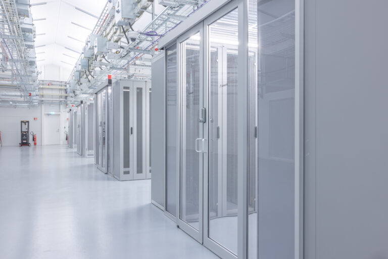Rows of server racks in a clean, modern AI-ready data center with glass doors and overhead cabling.