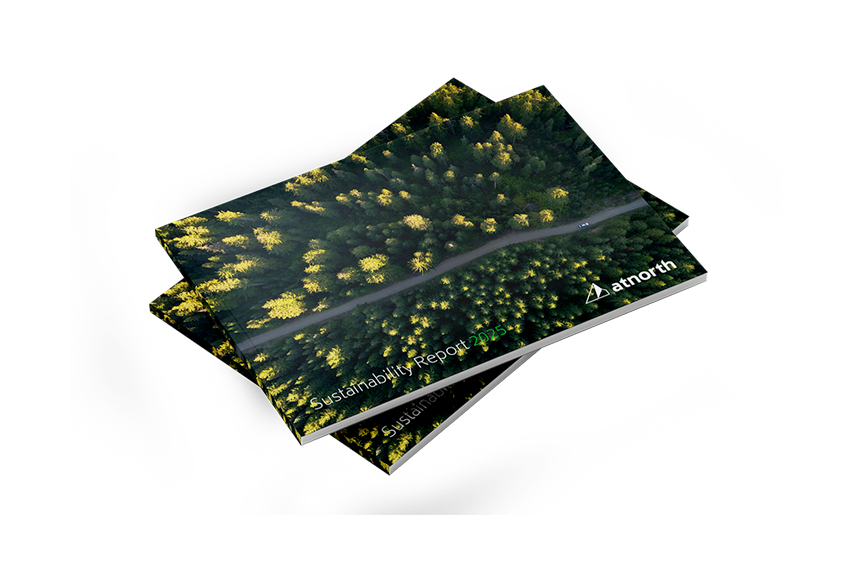A stack of booklets titled "Sustainability Report 2023" featuring an aerial view of a forest with a road, branded with the atnorth logo.