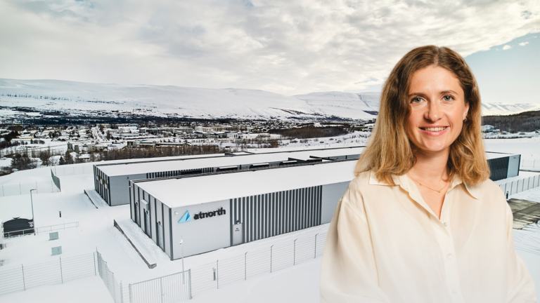 A smiling woman in a beige shirt stands in front of an AI-ready data center located in a snowy, mountainous landscape.